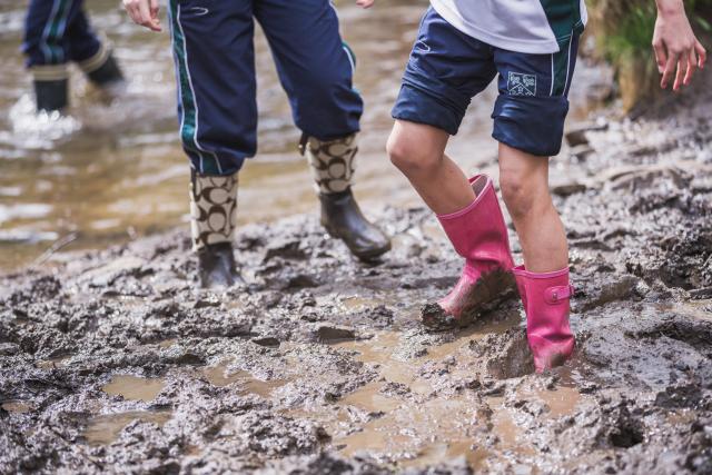A CLC pupil walks through a muddy river bank during a geography field trip