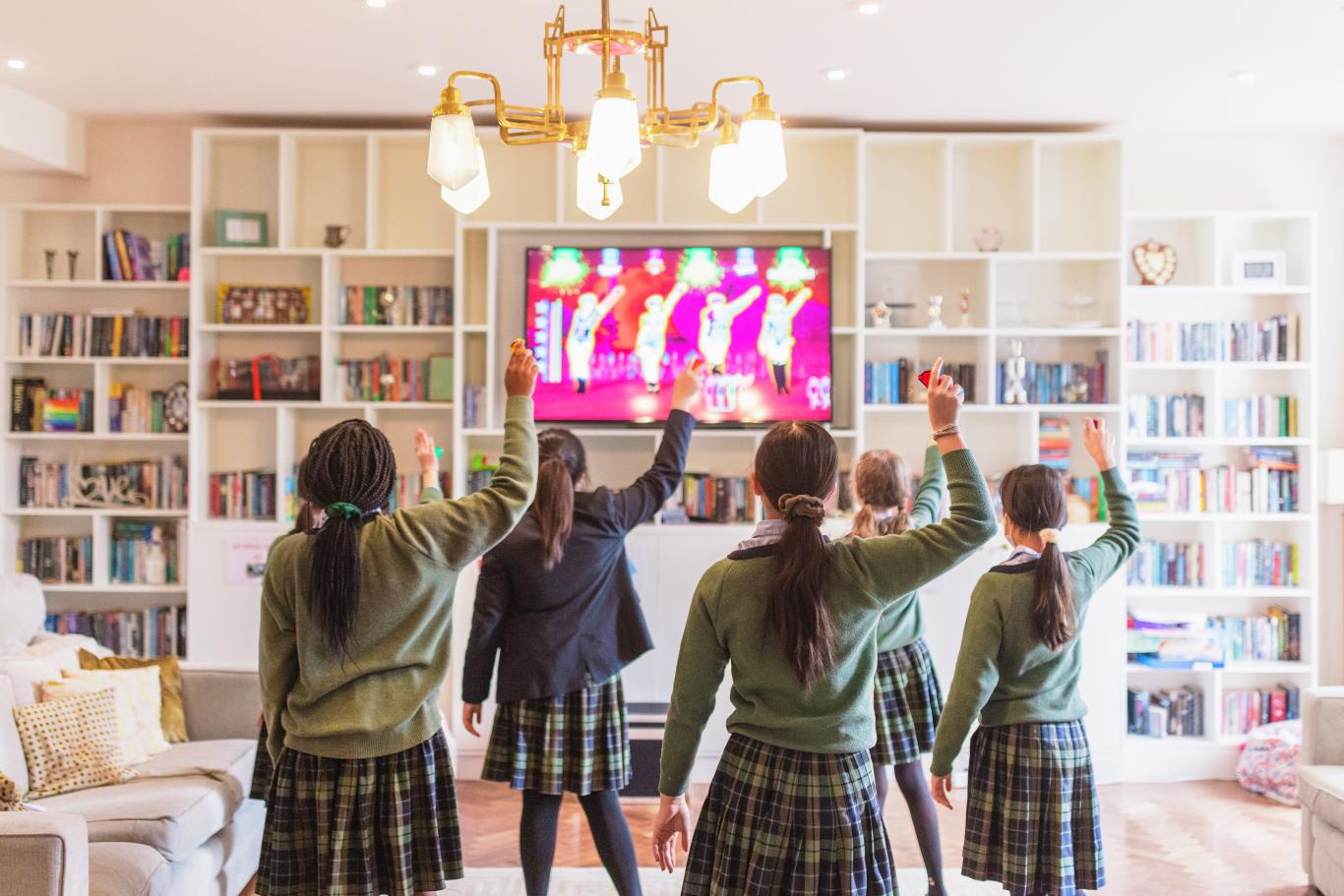5 students in CLC uniform dance to Just Dance on a Wii console