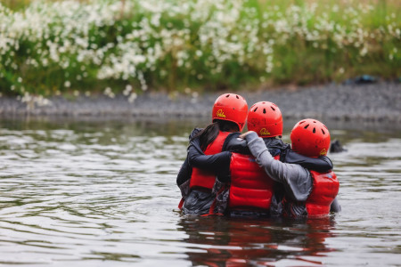 Teenagers hugging in a river on an outward bound day