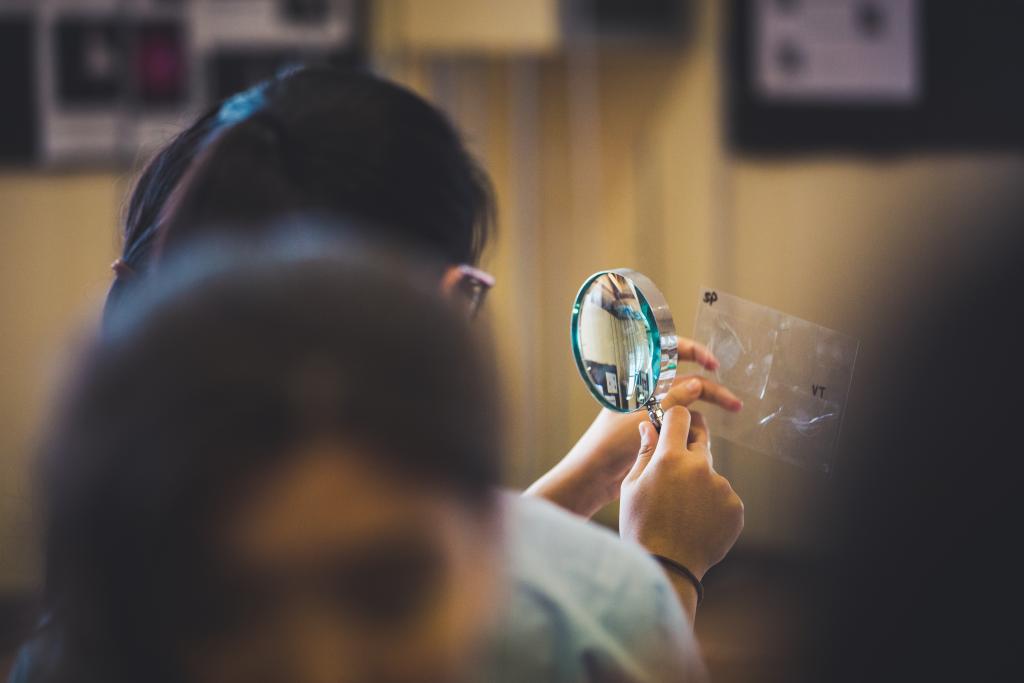 A CLC looks through a magnifying glass during a forensics chemistry lesson
