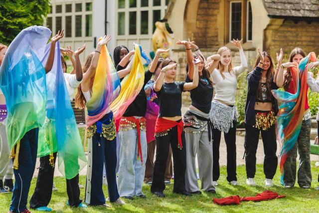 Students wearing colourful scarves dancing in the gardens