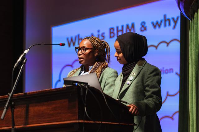 Two students of colour talk from the lectern during Prayers to launch Black History Month