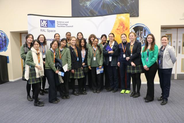 A group of 15 CLC students and their teachers pose for a photo in front in the lobby of the Space Laboratory