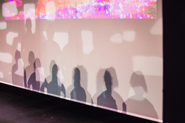 Shadows of students performing on the backdrop of the stage