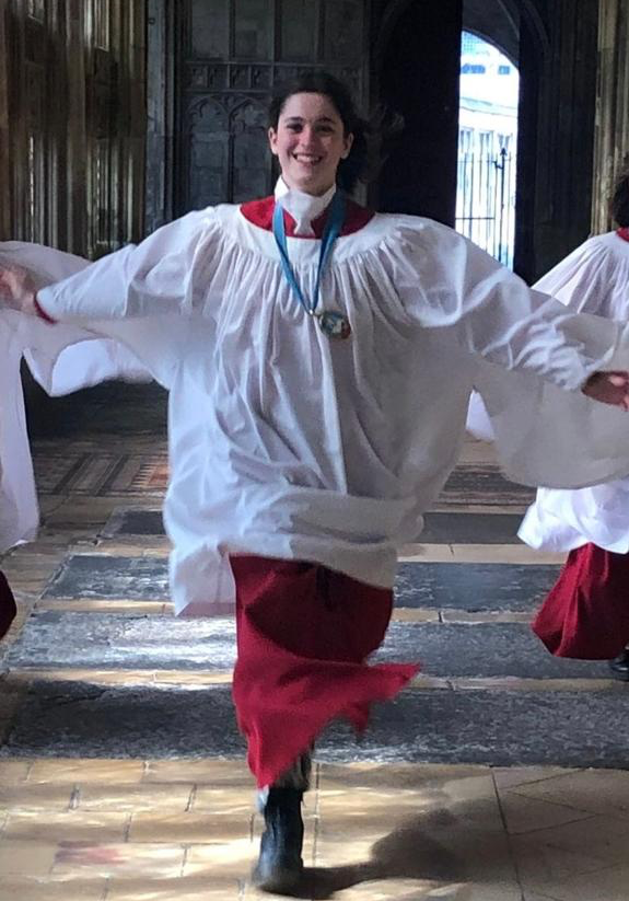 Year 9 pupil Livvie wearing her chorister robes running excitedly