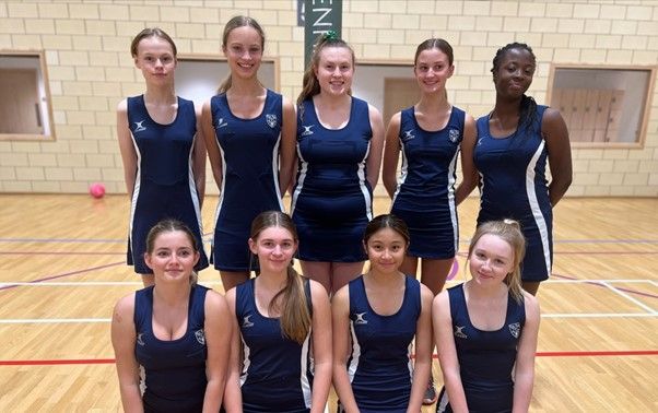 9 CLC netball players wearing their kit on the indoor netball court